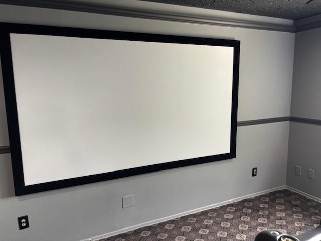 home theater room featuring carpet, a textured ceiling, and baseboards