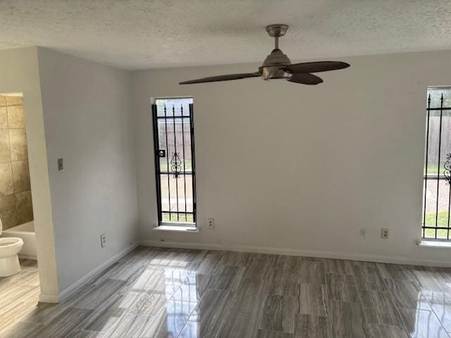 spare room with a ceiling fan, baseboards, a textured ceiling, and wood finished floors