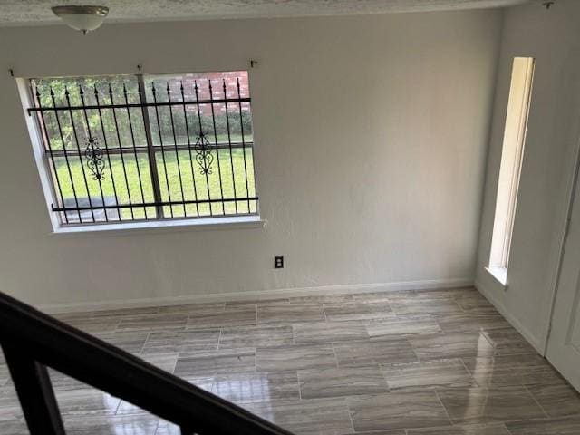 unfurnished room featuring baseboards and plenty of natural light