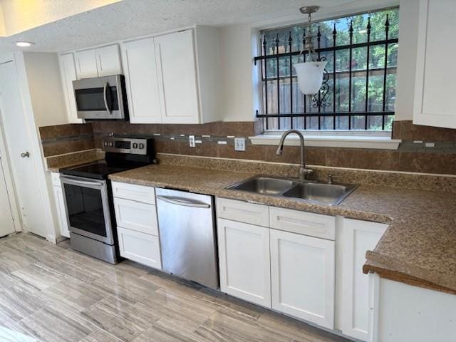 kitchen featuring a sink, dark countertops, white cabinets, appliances with stainless steel finishes, and decorative backsplash