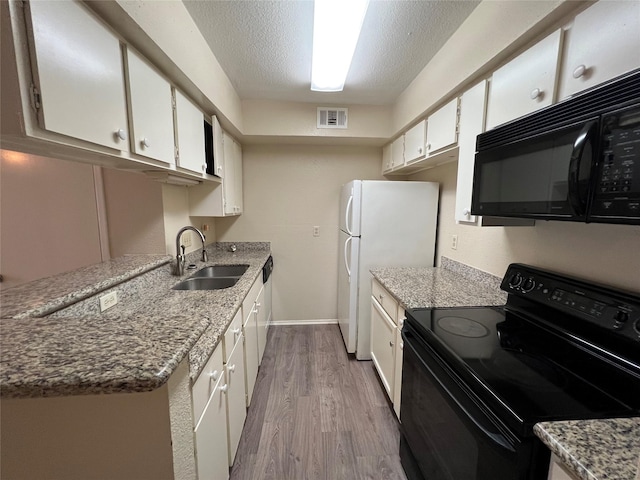kitchen featuring a sink, light wood-type flooring, black appliances, visible vents, and white cabinetry