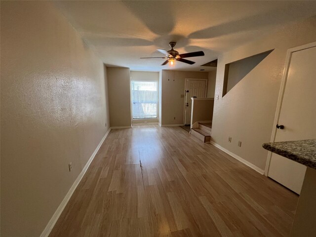 unfurnished living room featuring baseboards, light wood-style floors, and ceiling fan