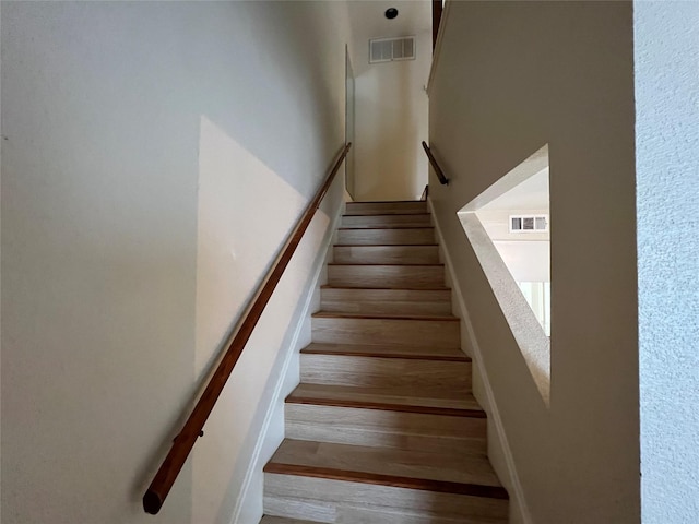 staircase with visible vents and wood finished floors