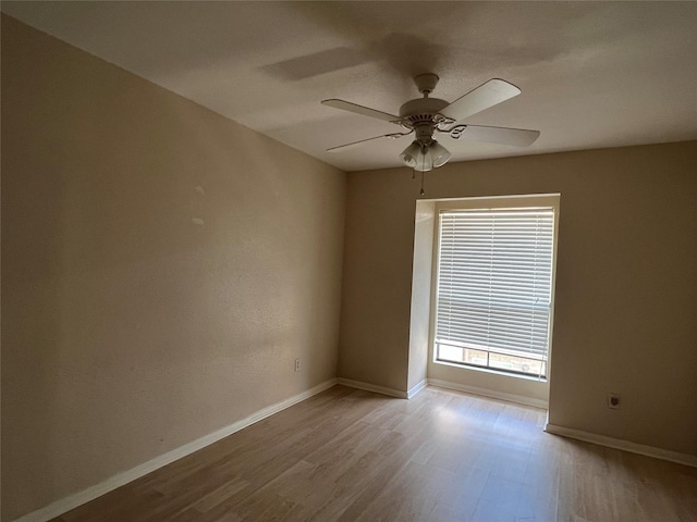 unfurnished room with baseboards, wood finished floors, and a ceiling fan