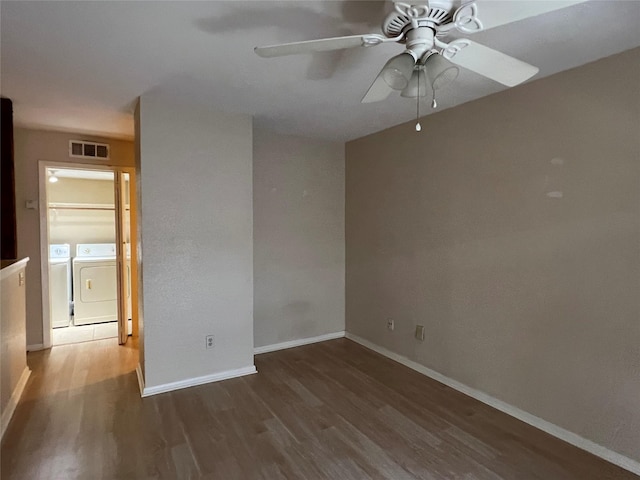unfurnished room with wood finished floors, a ceiling fan, washer and clothes dryer, visible vents, and baseboards
