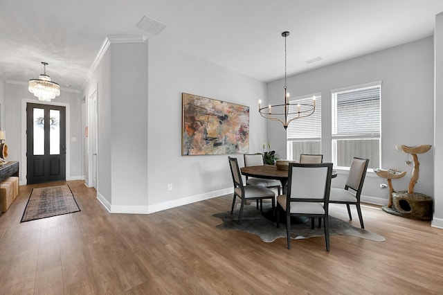 dining space featuring ornamental molding, a chandelier, and wood finished floors