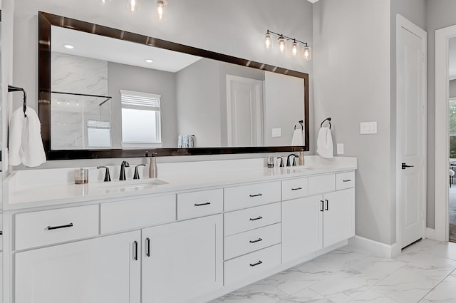 full bath with baseboards, marble finish floor, double vanity, and a sink