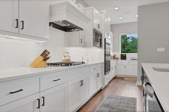 kitchen featuring premium range hood, light countertops, stainless steel appliances, and white cabinets