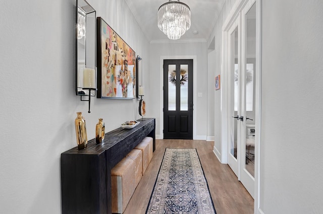 entryway featuring baseboards, ornamental molding, a chandelier, and wood finished floors
