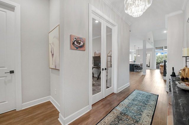 hallway with an inviting chandelier, ornamental molding, and wood finished floors