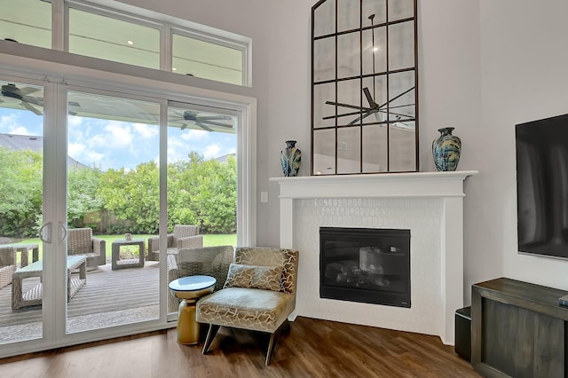 sitting room with ceiling fan, a glass covered fireplace, and wood finished floors