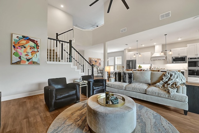 living area featuring visible vents, wood finished floors, and a ceiling fan