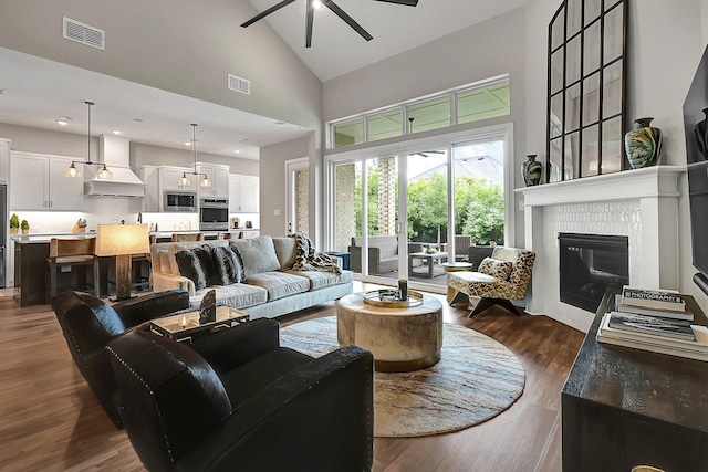 living area featuring high vaulted ceiling, a ceiling fan, visible vents, and dark wood finished floors
