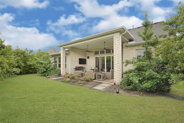 back of property with a lawn, a patio area, brick siding, and a ceiling fan