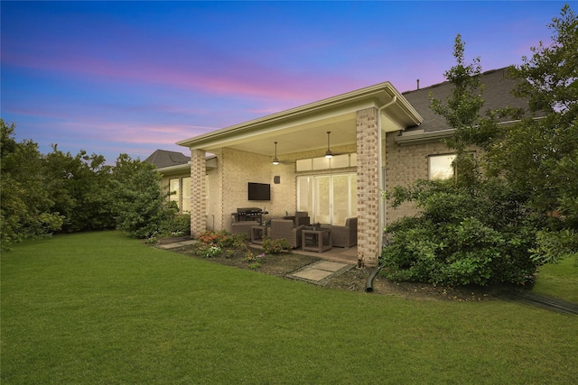 rear view of property featuring a yard, a patio area, and brick siding