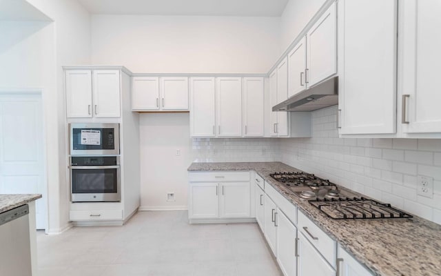 23403 Malbec Dr, Alvin, TX 77511 - kitchen featuring appliances with stainless steel finishes, under cabinet range hood, tasteful backsplash, white cabinets, and baseboards
