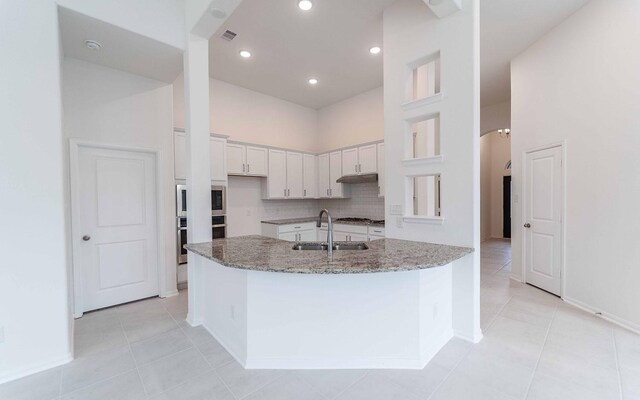 23403 Malbec Dr, Alvin, TX 77511 - kitchen featuring a sink, light stone counters, white cabinetry, light tile patterned floors, and a high ceiling