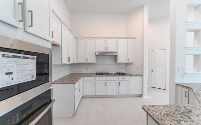 23403 Malbec Dr, Alvin, TX 77511 - kitchen with appliances with stainless steel finishes, under cabinet range hood, light stone countertops, and backsplash