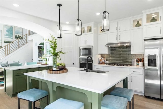 kitchen featuring a sink, appliances with stainless steel finishes, under cabinet range hood, light countertops, and light wood-style floors
