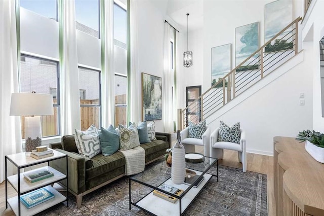 living area with a towering ceiling, stairs, and plenty of natural light