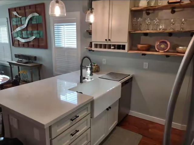 bar featuring hanging light fixtures, a sink, dark wood-style flooring, baseboards, and dishwasher