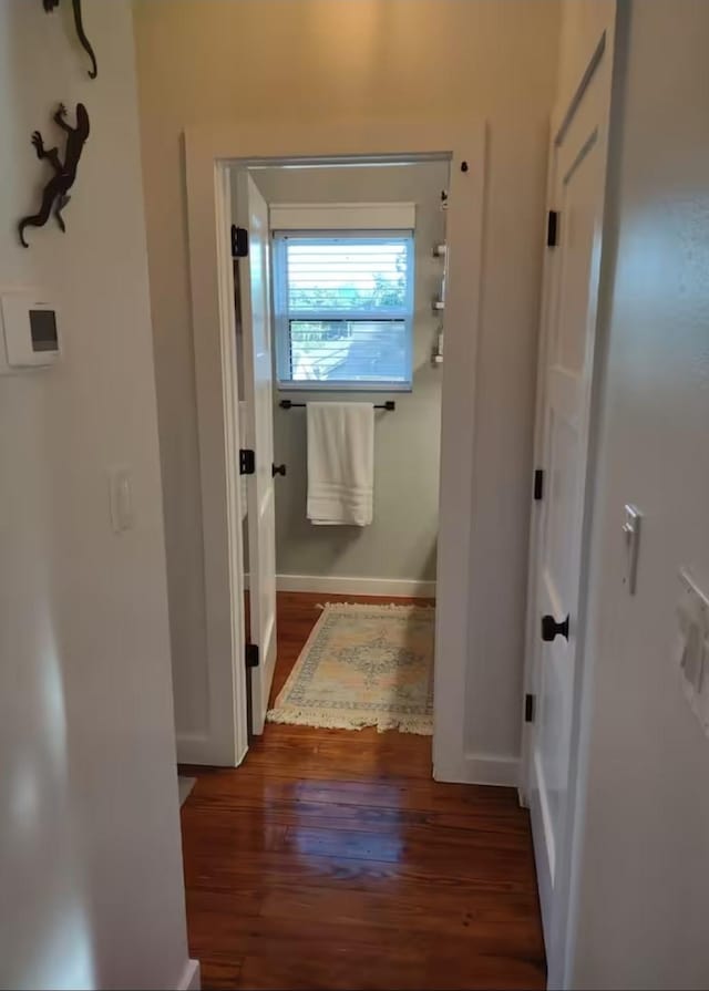 hallway featuring baseboards and wood finished floors