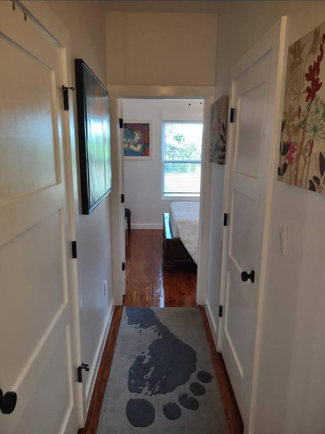 hallway featuring baseboards and dark wood-style floors