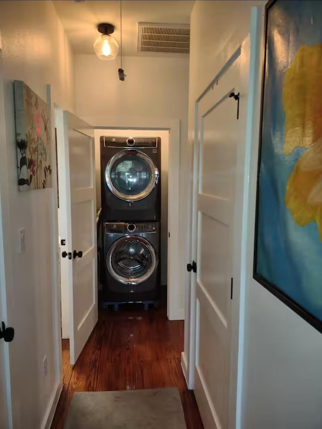 clothes washing area featuring visible vents, laundry area, stacked washer / dryer, and dark wood-type flooring