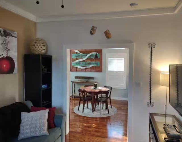 dining space with baseboards, crown molding, and wood finished floors