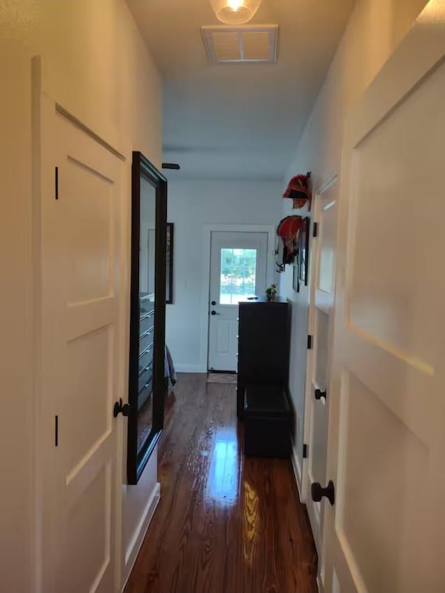 hallway with baseboards, dark wood-type flooring, and visible vents