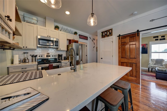 704 Burleson St, Brenham, TX 77833 - kitchen with stainless steel appliances, a barn door, backsplash, pendant lighting, and a kitchen breakfast bar