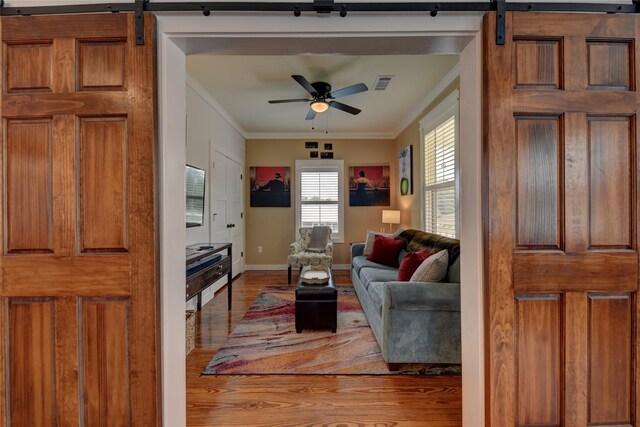 704 Burleson St, Brenham, TX 77833 - living room featuring a barn door, wood finished floors, crown molding, and a ceiling fan