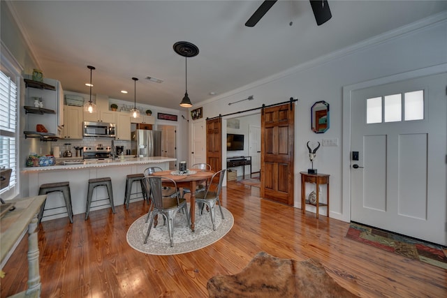 704 Burleson St, Brenham, TX 77833 - dining room with a barn door, a ceiling fan, crown molding, plenty of natural light, and wood finished floors
