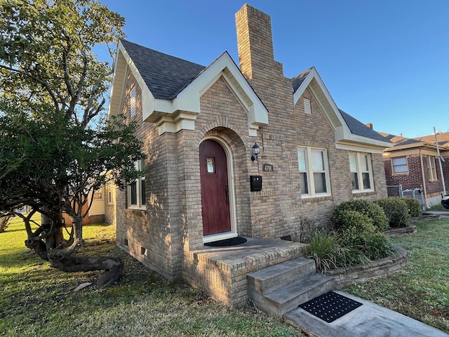 4701 Avenue N 1/2 Ave N 1/2, Galveston, TX 77551 - tudor home featuring a chimney, brick siding, and a shingled roof