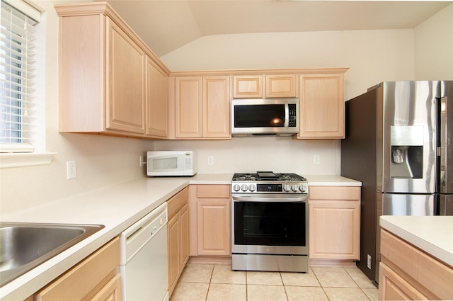 kitchen with light countertops, light brown cabinetry, appliances with stainless steel finishes, and vaulted ceiling