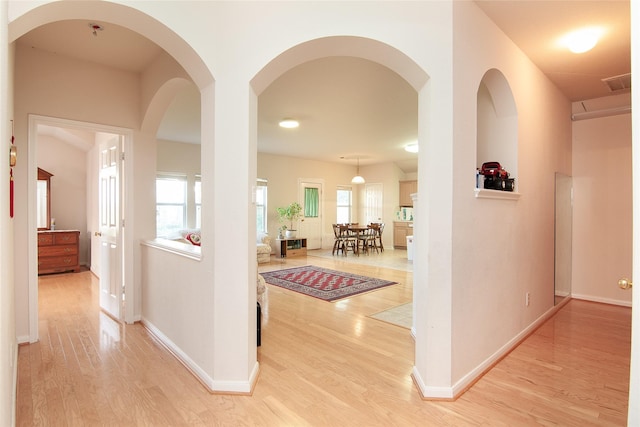 hall featuring visible vents, light wood-style flooring, and baseboards