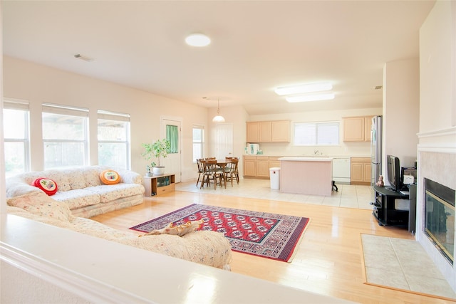 living room featuring light wood-style floors, a tiled fireplace, and visible vents