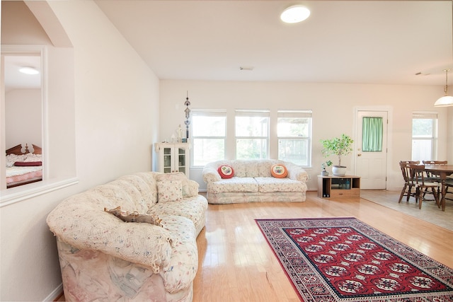 living room featuring arched walkways, light wood finished floors, and visible vents