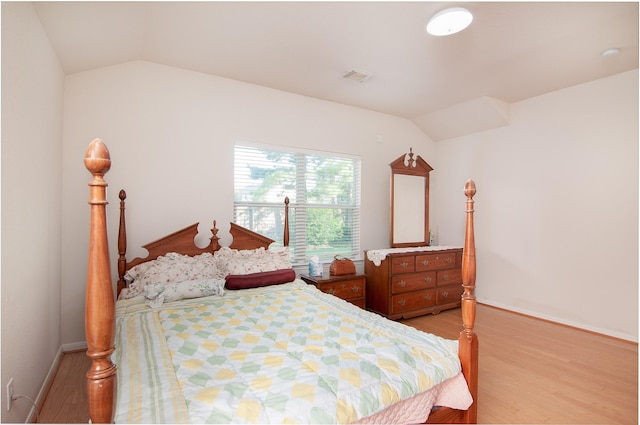 bedroom with lofted ceiling, light wood-style floors, visible vents, and baseboards