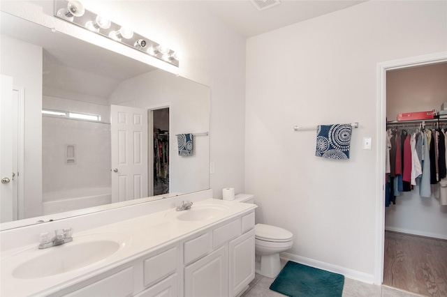 bathroom featuring a sink, double vanity, toilet, and baseboards
