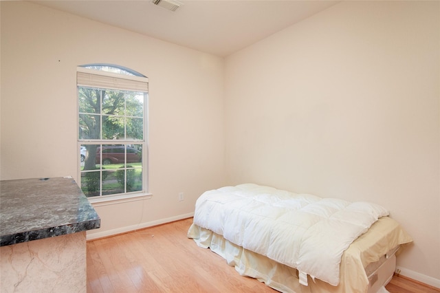 bedroom featuring baseboards, visible vents, and wood finished floors