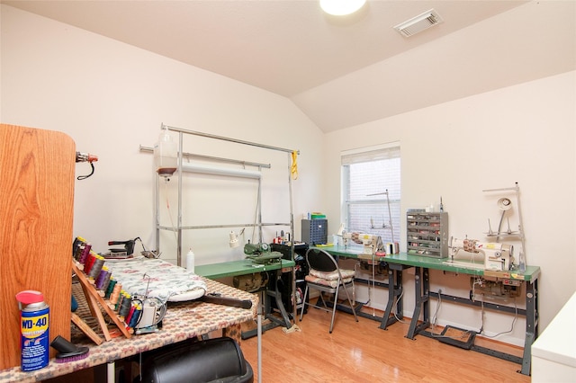 office area featuring vaulted ceiling, a workshop area, visible vents, and wood finished floors