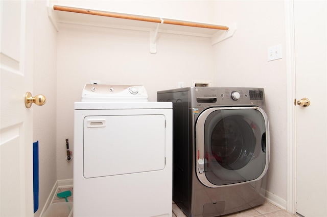 laundry room featuring washing machine and clothes dryer, baseboards, laundry area, and light tile patterned floors