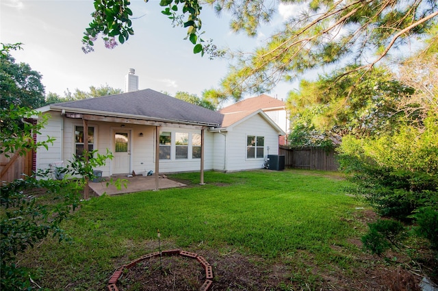 back of property with a chimney, fence, central AC unit, a yard, and a patio area