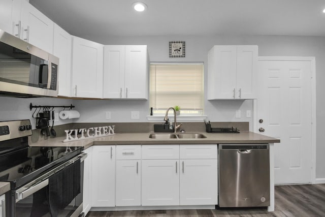 5410 Bataan Rd, Houston, TX 77033 - kitchen with stainless steel appliances, a sink, dark wood-type flooring, white cabinetry, and recessed lighting