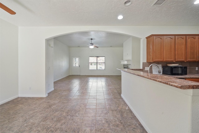 22981 Henson Rd, Montgomery, TX 77356 - kitchen with a textured ceiling, visible vents, ceiling fan, black microwave, and arched walkways