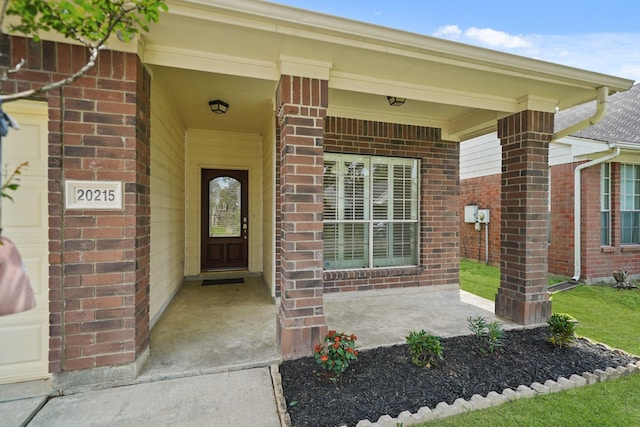 property entrance with covered porch and brick siding