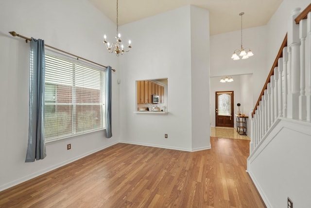 unfurnished dining area with an inviting chandelier, high vaulted ceiling, and stairs