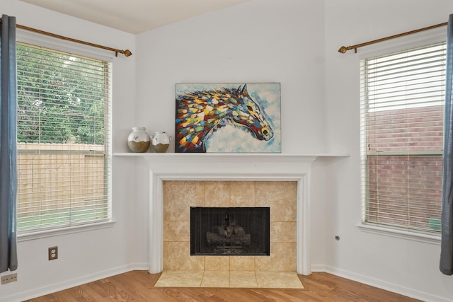 details with a tile fireplace, wood finished floors, and baseboards