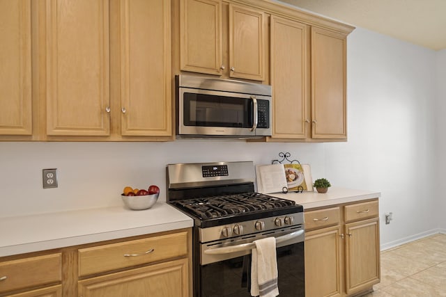 kitchen with light countertops, light tile patterned floors, stainless steel appliances, and light brown cabinets
